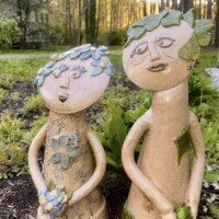 tan abstract sculptural shape of two figures decorated in flowers and leaves